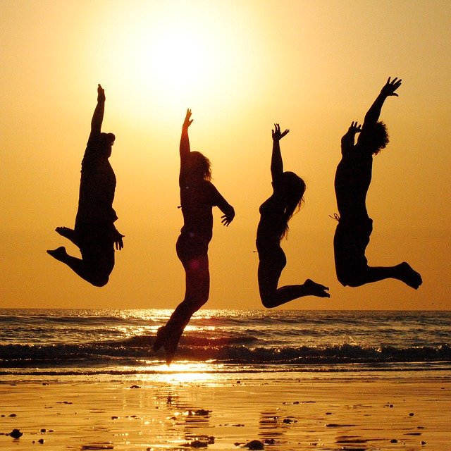 Ludzie skaczący przy zachodzie słońca na plaży